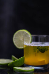 Drink, juice in a glass with a lemon slice, mint and cut lemons around.
