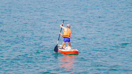 Surfer on stand up paddle board on blue wave, 
concept of an active lifestyle. 