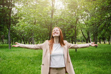 Bleisure Travel, bizcation concept, new trend in travel industry. Red-haired business woman enjoys vacation in park on nature background. Corporate traveller wants to enjoy leisure time during trip