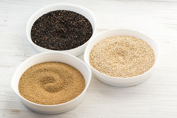 Set of healthy amaranth seeds and red and white quinoa.