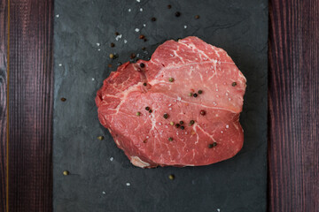 Meat on a black board. A sign on a wooden table. High quality photo. Meat with salt and pepper