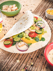 Fototapeta na wymiar Delicious tortilla wraps on wooden table with vegetable