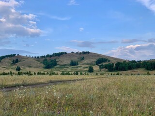 A stunning summer landscape with mountains, fields and forests. Beautiful sky.