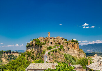 Fototapeta na wymiar View of the medieval town of Civita di Bagnoregio, located on the top of a spur of tuff rock, in the middle of the valley of the badlands. Connected to the city by a small bridge, mule track.