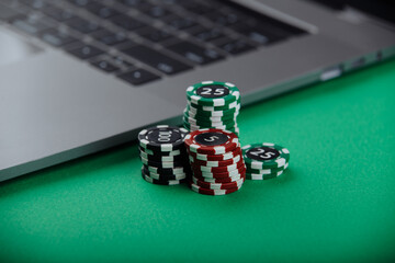 Casino chips and laptop on green background. Casino online concept.