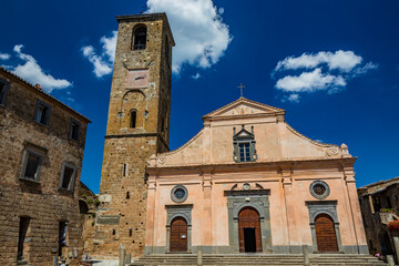 Fototapeta na wymiar Civita di Bagnoregio, Viterbo, Tuscia, Lazio, Italy. The Church of San Donato with the bell tower and the clock. Three wooden doors.