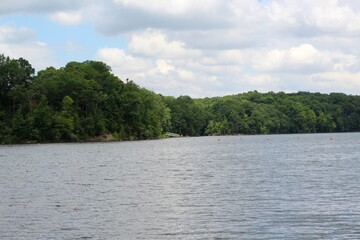 The lake in the country with the fluffy clouds in the sky.