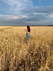 Naklejka na ściany i meble Young happy beautiful slender girl with long hair and a hat in a wheat field. Summer landscape