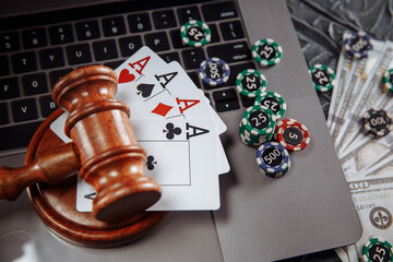 Judge wooden gavel, money banknotes and playing cards on computer keyboard, legal rules for online...