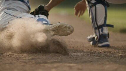 Sliding into home. A runner tries to slide into home plate. Back catcher tags the runner and it's a close call in a dustup. Shot in slow-motion and in 4k.  - Powered by Adobe