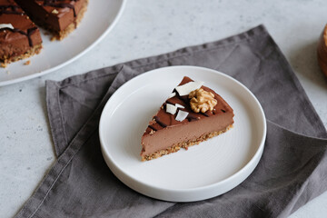 Piece of homemade chocolate raw vegan cake - healthy dessert made from coconut milk, butter, cashew, cacao, walnut