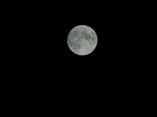 Genova, Italy - 07/05/2020: An amazing photography of the full moon over the city of Genova by night with a great clear and blue sky in the background and some stars.