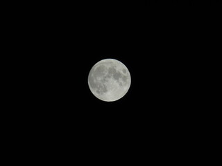 Fototapeta premium Genova, Italy - 07/05/2020: An amazing photography of the full moon over the city of Genova by night with a great clear and blue sky in the background and some stars.