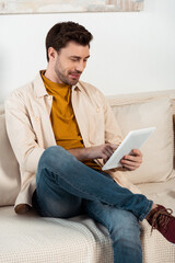 Handsome man using digital tablet on couch in living room