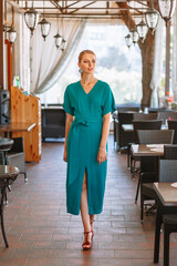 Model in a green long dress, clothing demonstration in a cafe