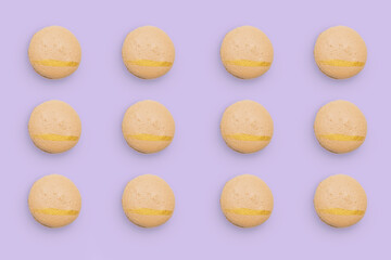 Macaroons pattern on colored background, twelve colorful french cookies macarons. Beige french cookies macarons on purple background. Gift for congratulations.