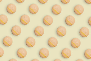 Macaroons pattern on colored background, a pattern of colorful french cookies macarons. Beige french cookies macarons on yellow background. Gift for congratulations.