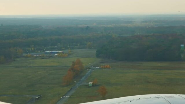 aerial view from airplane window on green fields and autumn forest
