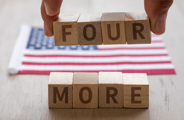 FOUR MORE concept on wood blocks fingers holding VOTE USA flag