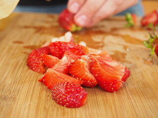 the cook cuts a large strawberry on a wooden Board. poster. in the summer