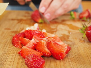 the cook cuts a large strawberry on a wooden Board. poster. in the summer