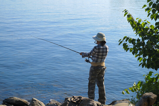 Woman Fishing Catching Fish On Blue Lake Water