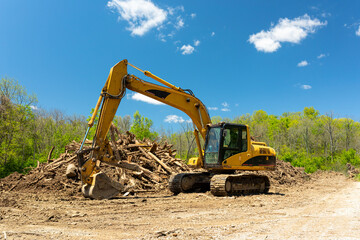 Excavator at work moving wood pile and earth. 