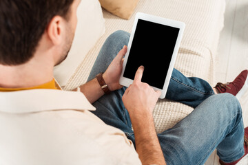 Selective focus of man using digital tablet with blank screen on couch