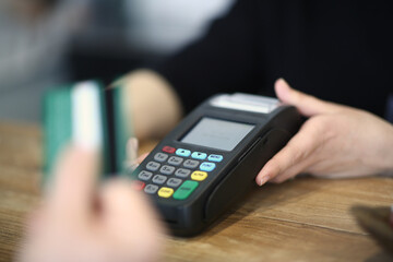 Close up of bartender with payment terminal and client hand with credit card. Modern technology and people concept
