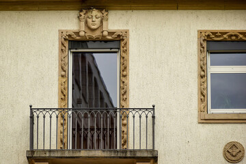 Fototapeta na wymiar A fragment of a building with a wrought-iron balcony and a bas-relief