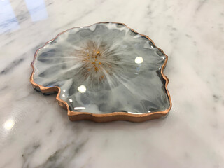 Cup holder, epoxy resin tray, marine-style stone cut. Blue stains of paint, gold trim. Subject for table setting. Gloss, reflection.