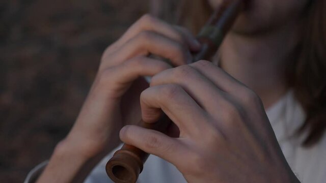 Close-up Medieval Ethnic Musician. Man with Long Hair Plays Flute in Wood. Evening Nature Scene. Slow motion - 60 FPS