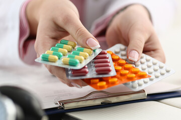 Close up of doctor holding different pills in hands and offering them to the patient in the clinic. Health and care concept