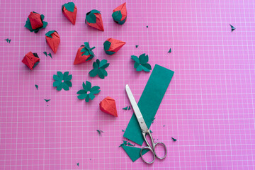Proceso de manualidades con fresas de papel, tijeras y tabla de corte rosa