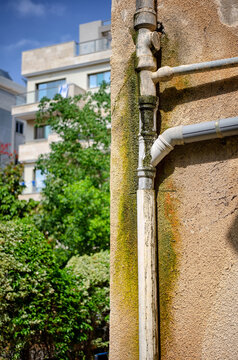 An old sewer pipe has been leaking for a long time on a wall of a residential house. 