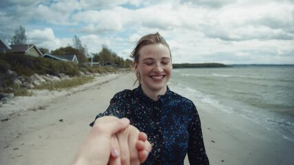 Smiling Blonde Woman Reaching Out Her Hand and Happily Walking by the Beach - Powered by Adobe
