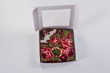 top view on small white gift box with soft cotton scarf with red rose ornament