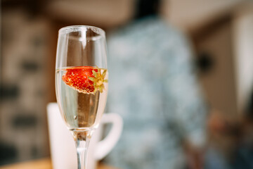 A glass of champagne with red strawberries inside.