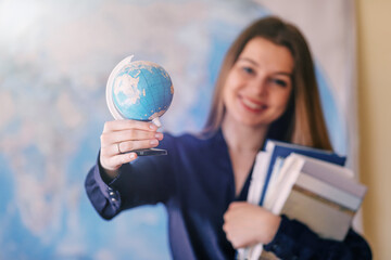 Young casual smiling woman student hold world globe, school book