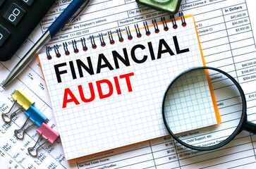 Obraz premium Text Financial Audit on notepad with calculator, clips, pen on financial report