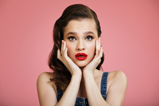 Portrait of beautiful surprised pin-up girl on pink background.