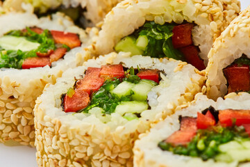 Vegetarian sushi rolls with cucumber, sweet pepper, and wakame seaweed on a white background