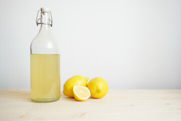 Lemonade in glass and bottle on wooden table. Lemonade or mojito cocktail with lemon and mint, cold refreshing drink or beverage with ice. Copy space for your text