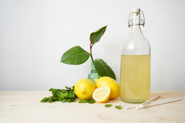 Lemonade in glass and bottle on wooden table. Lemonade or mojito cocktail with lemon and mint, cold refreshing drink or beverage with ice. Copy space for your text