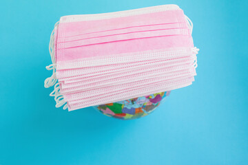 Medical masks and globe on a blue background with space.
