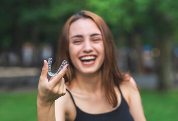 Beautiful smiling Turkish woman is holding an invisalign bracer with vibrant colors