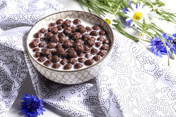 Obraz na płótnie Canvas Breakfast cereal, Chocolate cereals in milk with cornflower flower on a natural napkin , concept of healthy nutrition for children, soft focus.