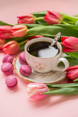 Cup of coffee with tulips on a pink background, romantic photo