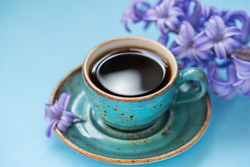 Cup of coffee with blue hyacinth on a blue background