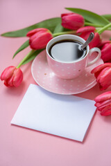 Pink cup of coffee with tulips on a pink background. Concept